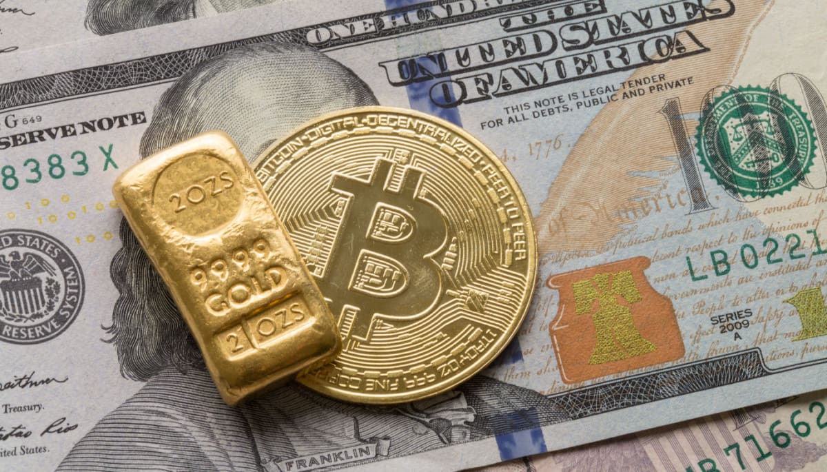 Een afbeelding van een bitcoin (BTC) munt naast een gouden bullion, liggend op een dollar biljet
